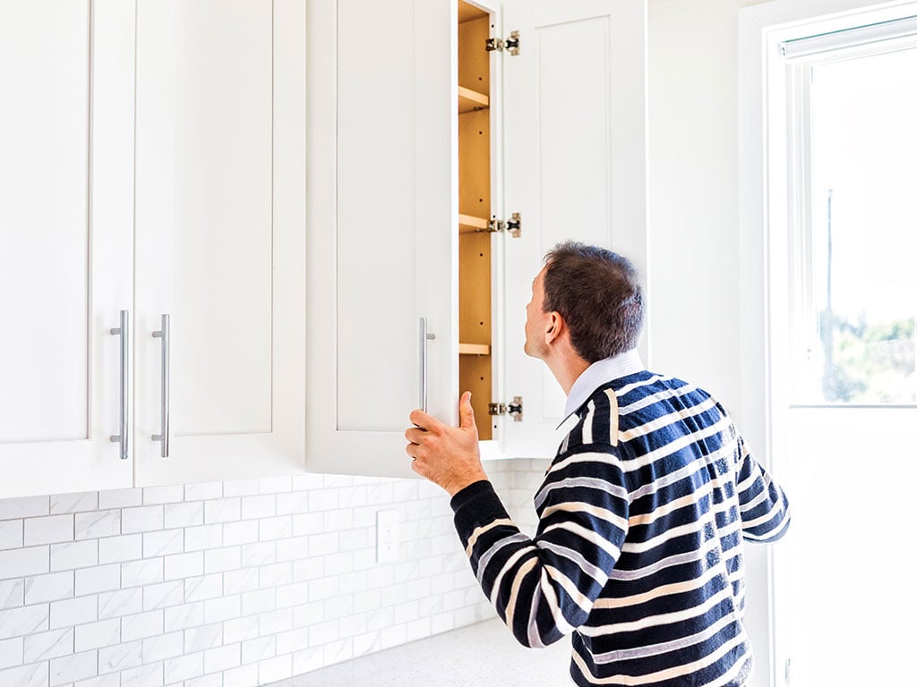 Man looking in kitchen cabinets