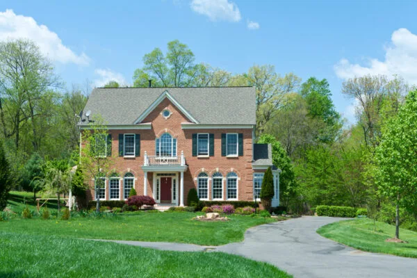 Two-story brick home with a landscaped front lawn and curved driveway.