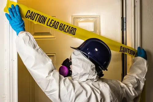 Certified contractor securing a lead hazard area in a rental property with lead paint warning tape