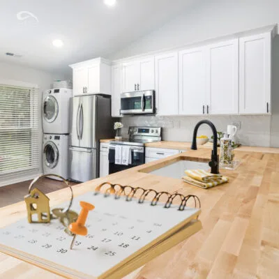 Modern kitchen with white cabinets with a calendar and house key overlay symbolizing rent due dates