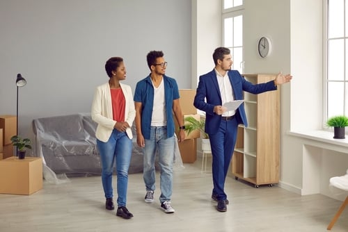 Real estate agent showing a couple around an unfurnished apartment.