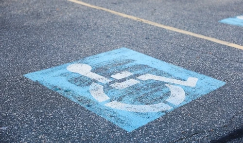A close-up of a blue-painted handicapped parking symbol on an asphalt surface.