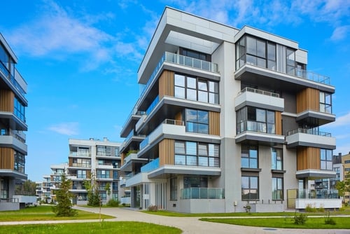 Modern apartment buildings with large windows and balconies on a sunny day.