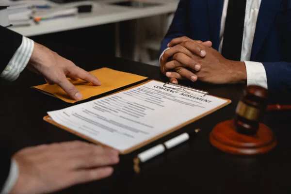 Discussion of HOA legal violations with a contract agreement, gavel, and pen on a desk.