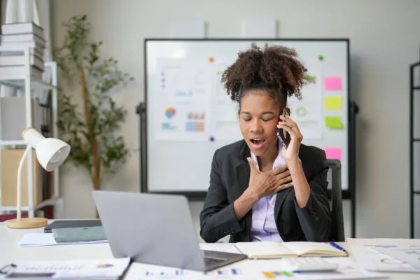 Young female landlord, visibly overwhelmed while juggling tasks and a phone call.