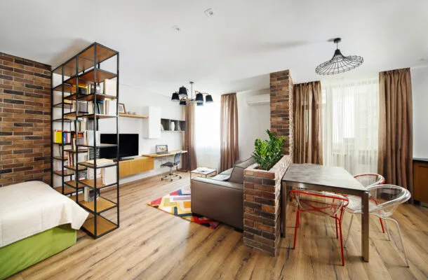 Interior studio apartment with bookshelves and hardwood floors.