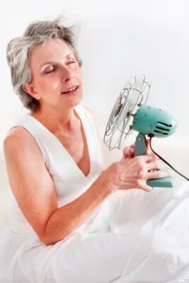 A woman using a fan to cool off.