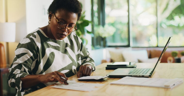 woman budgeting with a laptop and bills in hand