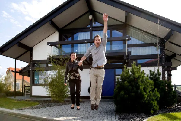 Happy couple celebrating outside their new single-family home with modern design and large windows.