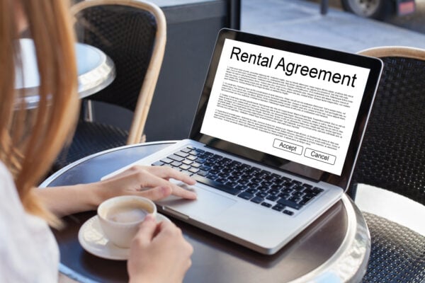 Person reviewing rental agreement contract on laptop in a café