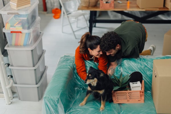 Young couple moving in a new apartment, lying on the sofa with their dog