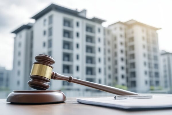 Gavel and legal documents in front of apartment buildings, symbolizing real estate laws and best practices for ROFO and ROFR clauses.