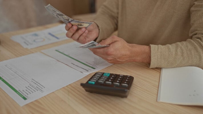 Landlord counting rent payment with documents and calculator on the table