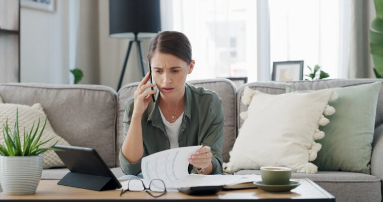 A worried tenant reviewing bills and calling about a rent payment issue caused by a failed bank transfer