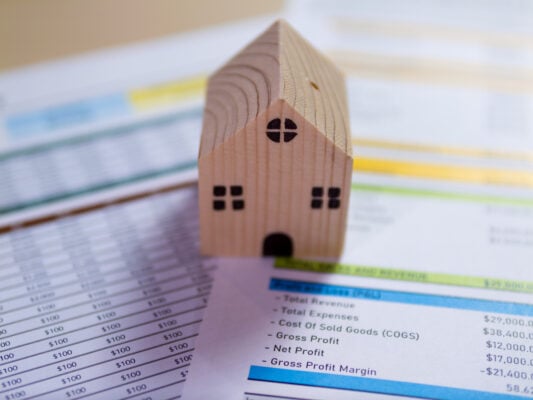 Wooden house model on financial spreadsheet representing pro forma rent projection in real estate.