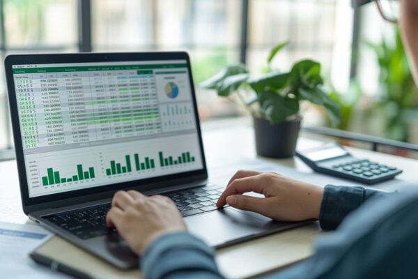 Investor reviewing rental income projections and financial data on laptop spreadsheet.