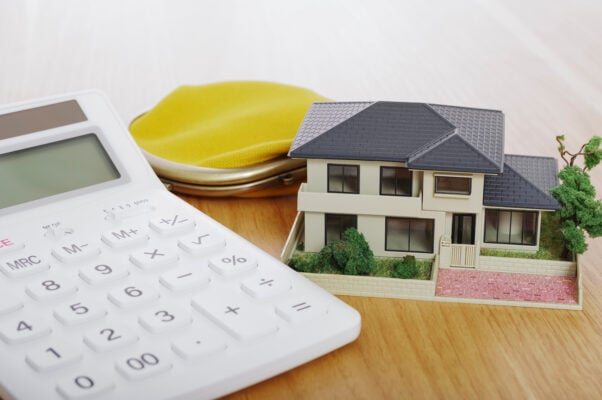 Calculator and model house illustrating rental property remodeling expenses and tax deductions