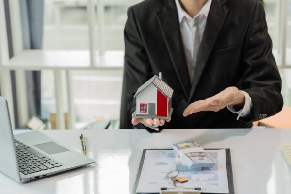 Property manager reviewing documents while holding a model house to plan rental remodeling and tax timing