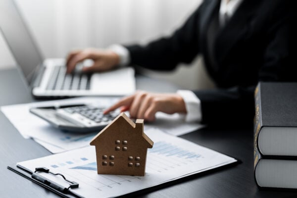 Real estate investor reviewing tax documents with house model and calculator