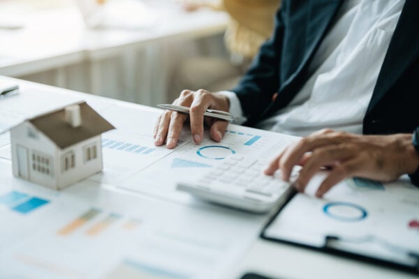 Real estate investor calculating rental income projections with calculator and financial charts.