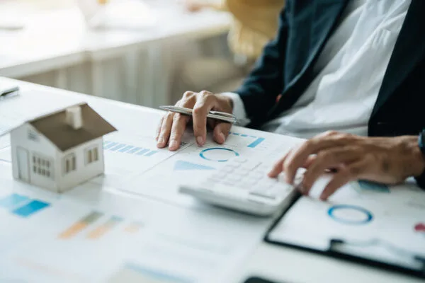 Real estate investor calculating rental income projections with calculator and financial charts.