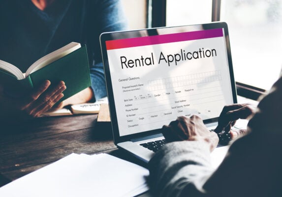 Person reviewing rental application on laptop during tenant screening process