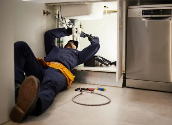 Maintenance technician fixing plumbing issues in a rental property