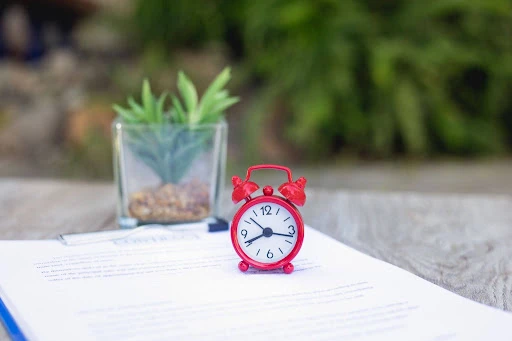 Alarm clock on rental paperwork representing the tenant screening timeline.