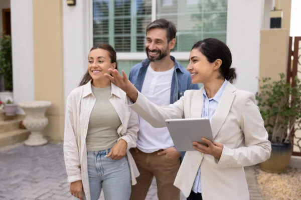 Property manager speaking with rental property clients outside a home